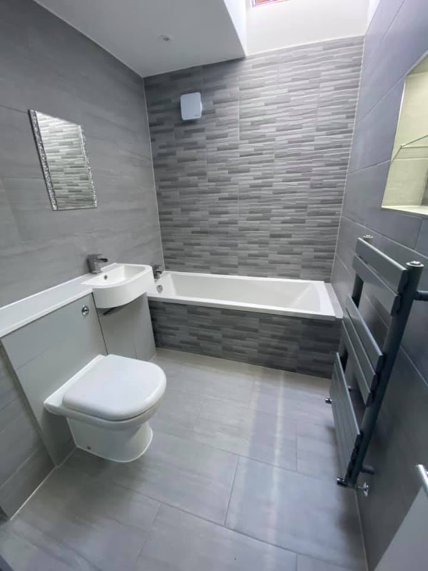 A darker-coloured bathroom illuminated by the skylight as light streams in from the top right of the frame