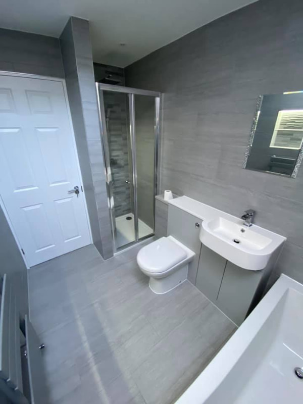 A reverse angle of Graham's bathroom showing the sink unit, toilet and shower from directly under the skylight