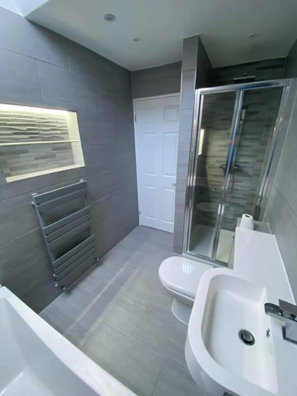 Another angle focusing on the door, radiator and inset illuminated shelving on the wall