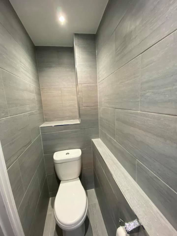 View down a narrow side room showing another toilet