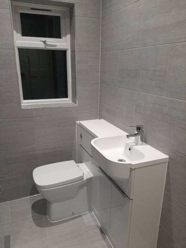 Close-up of the combined sink and toilet unit, showing the dark tiling attached to it.