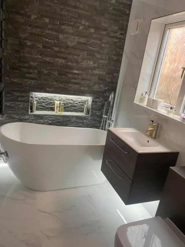 Another view focused on the sink unit and showing the window above it. The inset shelving for toiletries next to the bath can also be seen.